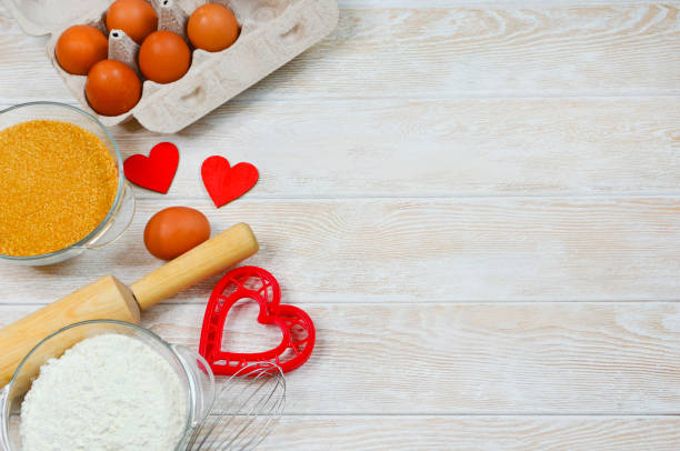 istock red festive ingrediens for cooking, valentines day eggs in eco package, rolling pin and whisk, cutter dish shape heart for baking cake flat lay 1364721766