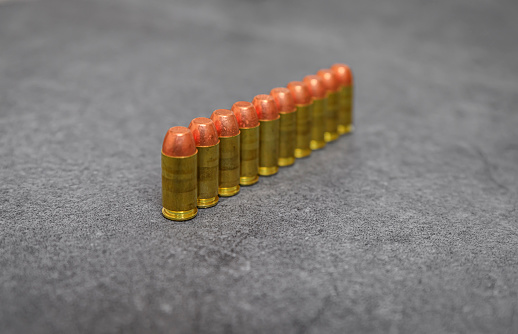 45 ACP caliber full metal jacket bullets unfired rounds lined up on a stone surface