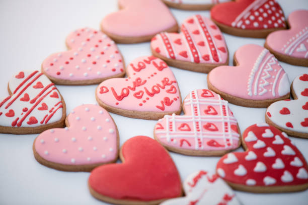 Top view homemade gingerbread Valentine's day with inscription - Love, cookies heart shapes decorated with colored royal icing and colorful patterns. Holiday food. Handmade patterns top cookies. stock photo