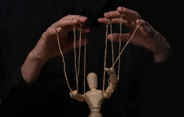 Hands manipulating wood puppet. Master of marionette.