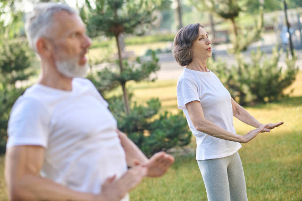 istock Mid aged people having yoga class in the park 1364725677