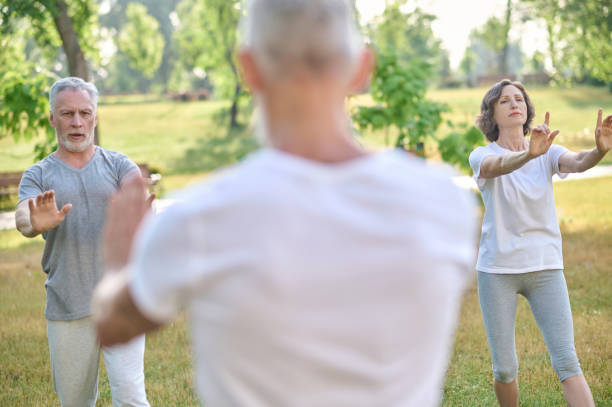 istock Mid aged people having yoga class in the park 1364725679