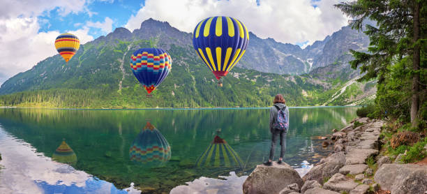 Young girl looks at hot air balloons over Morskoe Oko lake, Sea eye, Poland stock photo