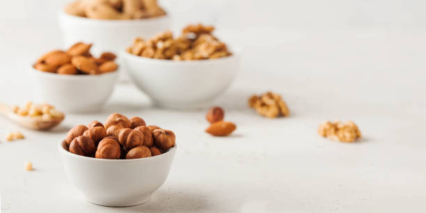 istock Hazelnuts and other nuts in white bowls on a white background. Banner 1364726903