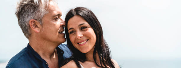 istock Horizontal banner or header with happy couple with beautiful woman and middle aged cool man standing against a sea landscape during the summer vacation 1364727607