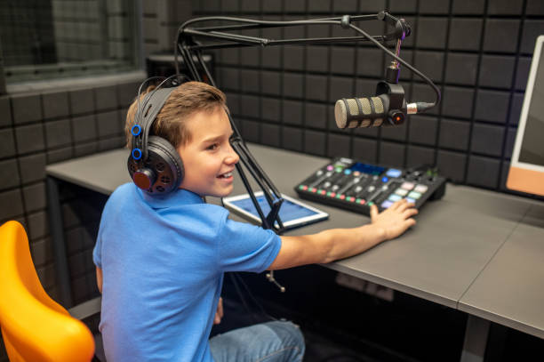 istock Joyous young boy sitting in the recording studio 1364728602