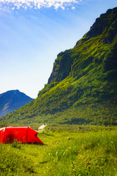 Blue tent on Gimsoysand beach in summer. Mountains on sea horizon. Camping on ocean shore. Lofoten archipelago Norway. Holidays and adventure.