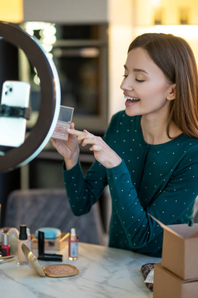 istock Young smiling woman shpowing new eyeshadows to onine audience 1364732386