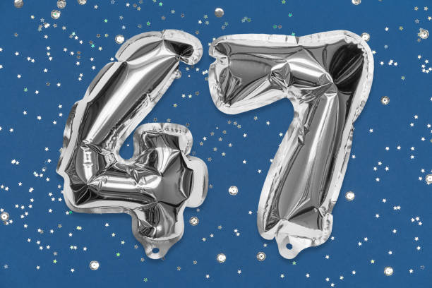 istock Silver foil balloon number, digit forty seven on a blue background with sequins. Birthday greeting card 1364734484