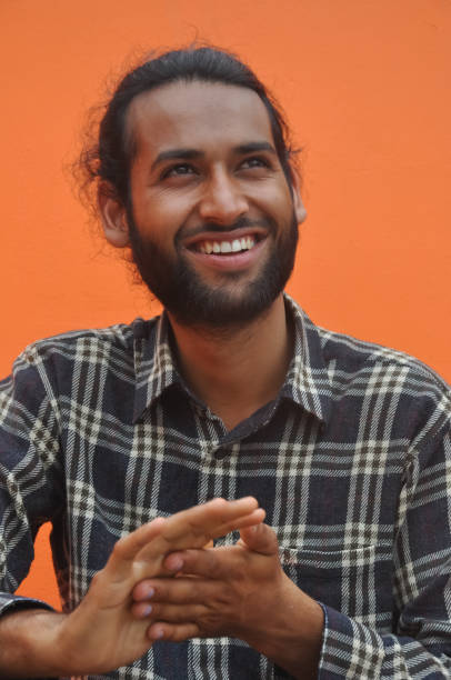 istock Selective focus of a bearded young man smiling while looking sideways, posing against orange wall background 1364735784
