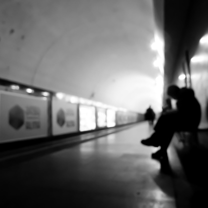 Lonely blurry silhouette of a young man sitting on the bench in subway