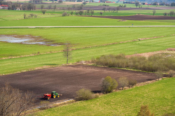Tractor sowing on a field in spring Falköping, Sweden - May 05, 2018: Tractor sowing on a field in spring patchwork landscape stock pictures, royalty-free photos & images