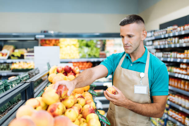 istock Employee in supermarket arranging fresh fruit 1364737890