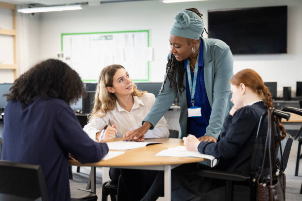 étudiantes travaillant sur des devoirs avec l’aide d’un enseignant - disabled teenager adolescence physical impairment photos et images de collection