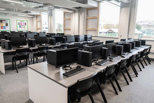 Wide angle view of organized flexible workstations providing students with monitor, keyboard, and mouse at each place for individual work.