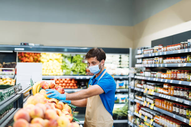 istock Employee with face mask in supermarket arranging fresh fruit 1364738039