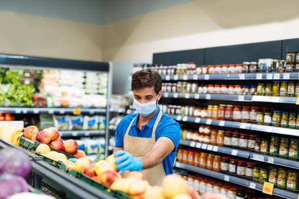istock Employee with face mask in supermarket arranging fresh fruit 1364738043
