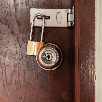 A close-up view, the golden knobs and keys lock tightly against the brown wooden door, forming a double protection.