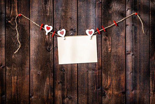 Valentines day background: blank card hanging on a rope shot against weathered wood table. High resolution 42Mp studio digital capture taken with Sony A7rII and Sony FE 90mm f2.8 macro G OSS lens