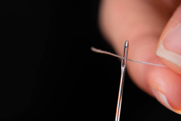 istock A hand threads a thread through the eye of a sewing needle. Sewing and needlework classes.Craft and handmade workshop.Workplace in the textile industry. Needle for embroidery by hand 1364742420