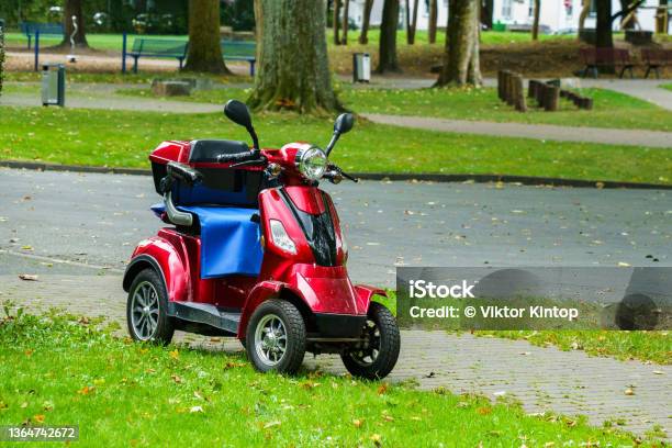 A Fourwheeled Red Motor Scooter Standing On The Side Of The Road Stock Photo - Download Image Now