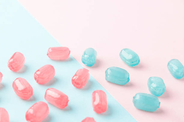 ミントブルーとピンクのパステルの背景にカラフルなロリポップ。甘いキャンディのコンセプト。クローズアップ、選択的なフォーカス。愛と優しさの最小限の概念 - lolly pop ストックフォトと画像