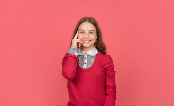 istock pondering happy kid in school uniform on red background, student 1364744301