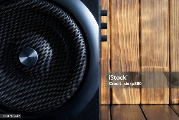A Large Loud Subwoofer In A Wooden Case With A Metal Grille And Volume And Tone Controls Stands Against A Background Of Natural Planks Audiophile Concept Scandinavian Style Stock Photo - Download Image Now