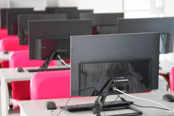 A variety of computer monitors or monoblocks - panel pc installed on tables in a library, classroom or call center. Selective focus. Without people
