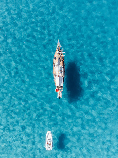 vista aerea di una barca a vela e di un motoscafo contro l'acqua limpida del mare turchese - recreational boat motorboat speedboat aerial view foto e immagini stock