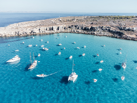 Many boats moored in Cala Rossa, one Favignana Island's beach. Clear turquoise water.