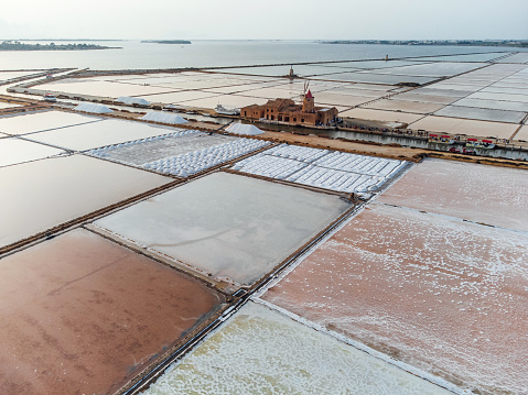 Aerial view of salt flats with windmills in Sicily, Italy, at sunset. Multi colored Saline di Marsala.