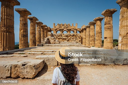 istock Rear view of a woman with a hat while she's admiring an ancient temple in Sicily 1364745633