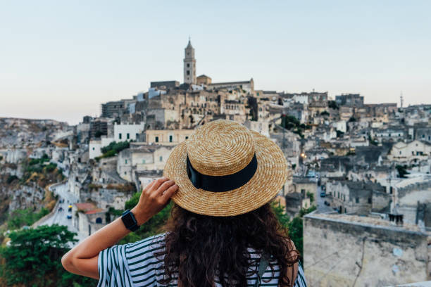 une femme avec un chapeau de paille admire la belle ville antique de matera - matera photos et images de collection