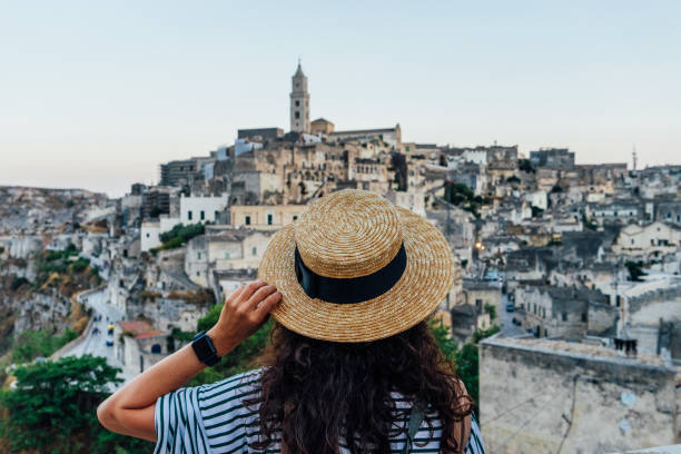 a woman with a straw hat is admiring the beautiful matera ancient city - matera imagens e fotografias de stock