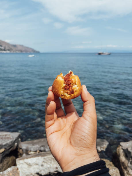 istock Holding an arancino against the sea in Sicily 1364746419