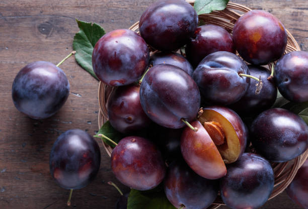 istock Ripe juicy plums on a wooden background. 1364748028