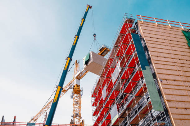 istock Crane lifting a wooden building module to its position in the structure. The new structure will be built in modular timber construction. 1364748737