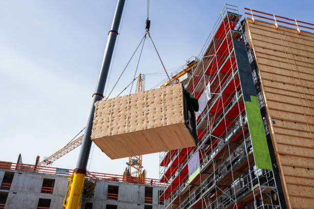 Crane lifting a wooden building module to its position in the structure. The new structure will be built in modular timber construction. stock photo