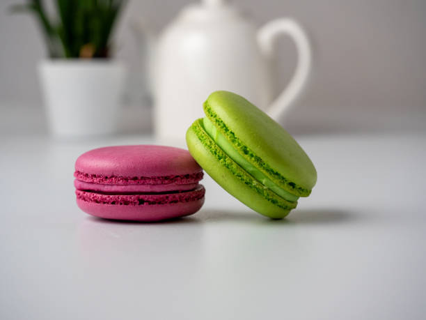 istock Colorful delicious macaroons lie on a white table. In the background is a white teapot and a flower 1364748778