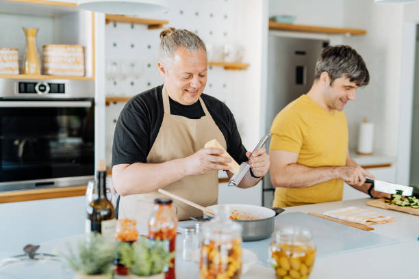 istock Mature gay couple cooking lunch at home, using online tutorial 1364750737