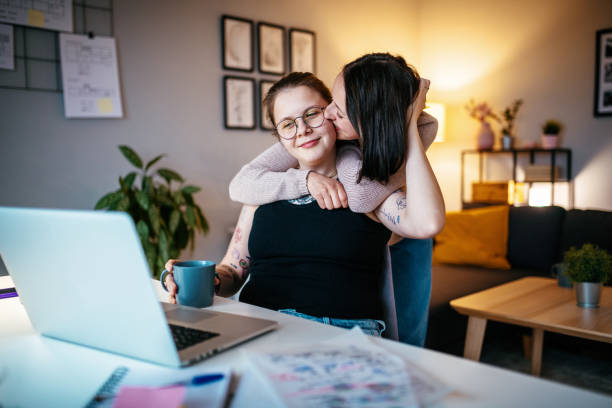 istock Lesbian couple kissing while working from home 1364751655
