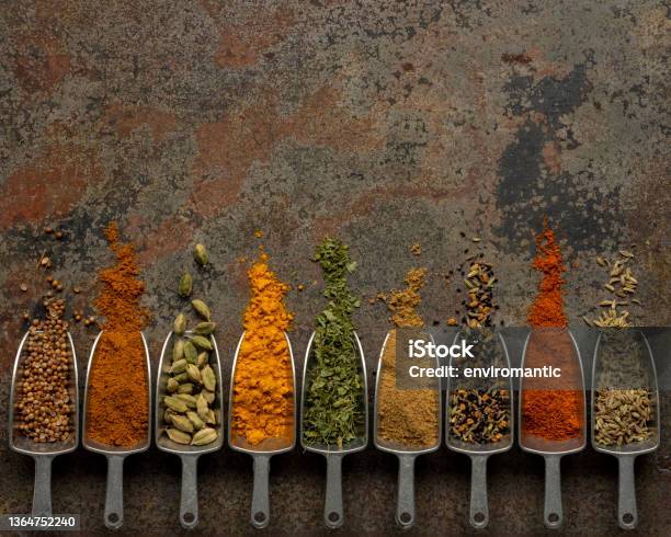Many Colorful Organic Dried Vibrant Indian Food Spices In Metal Measuring Dried Food Scoops On An Old Weathered Abstract Metal Background Stock Photo - Download Image Now