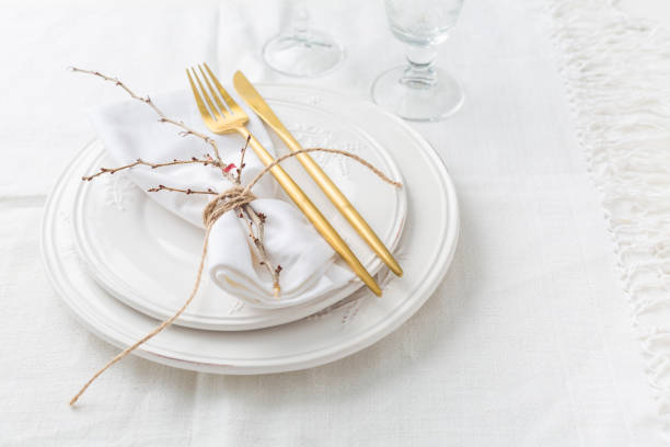 istock Place setting in white - plates, cutlery in gold, napkin 1364753823