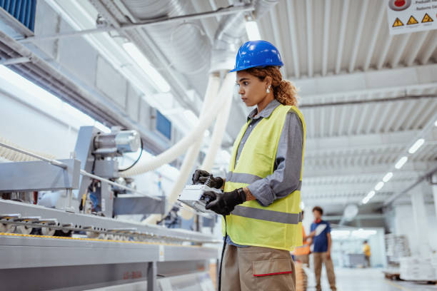 Engineers, architects and blue collar workers in protective clothing working in factory with modern machinery