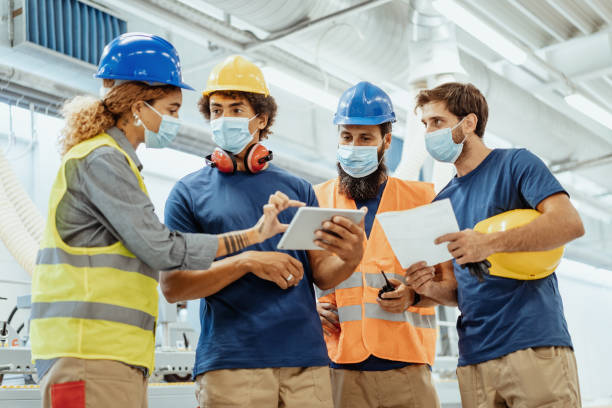 istock Employees in factory wearing face masks during pandemic, using digital tablet during brief meeting 1364753995
