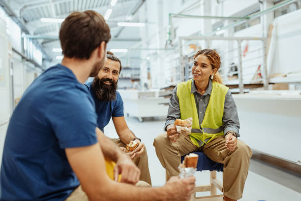 Teamwork in industry, employees eating breakfast Engineers, architects and blue collar workers in protective clothing working in factory with modern machinery construction lunch break stock pictures, royalty-free photos & images