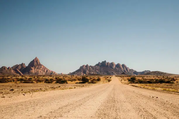 Panoramic view of the desert road with rocky landscape on the background in Spitzkoppe, Namibia