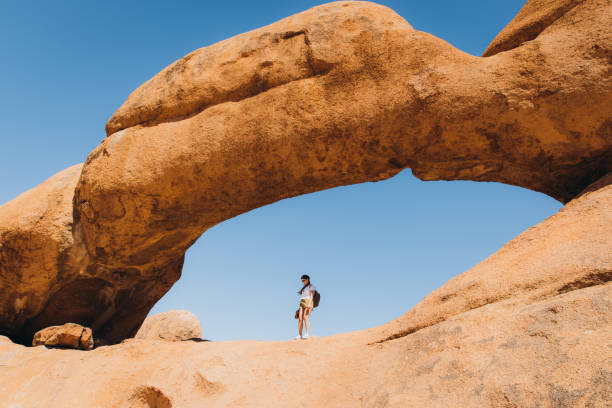 istock Female traveler exploring Spitzkoppe walking inside of the natural arch 1364754729
