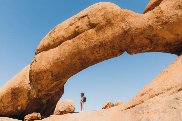 istock Female traveler exploring Spitzkoppe walking inside of the natural arch 1364754745